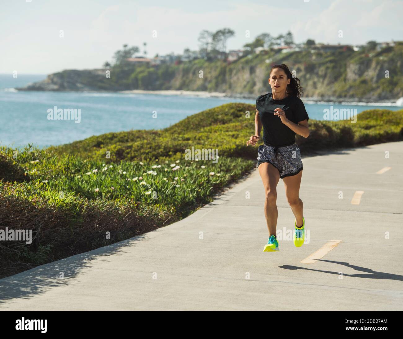 États-Unis, Californie, Dana point, femme en train de courir sur la route le long de la côte Banque D'Images