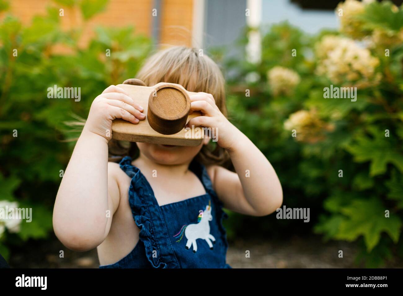 Petite fille (2-3) avec appareil photo dans le jardin Banque D'Images