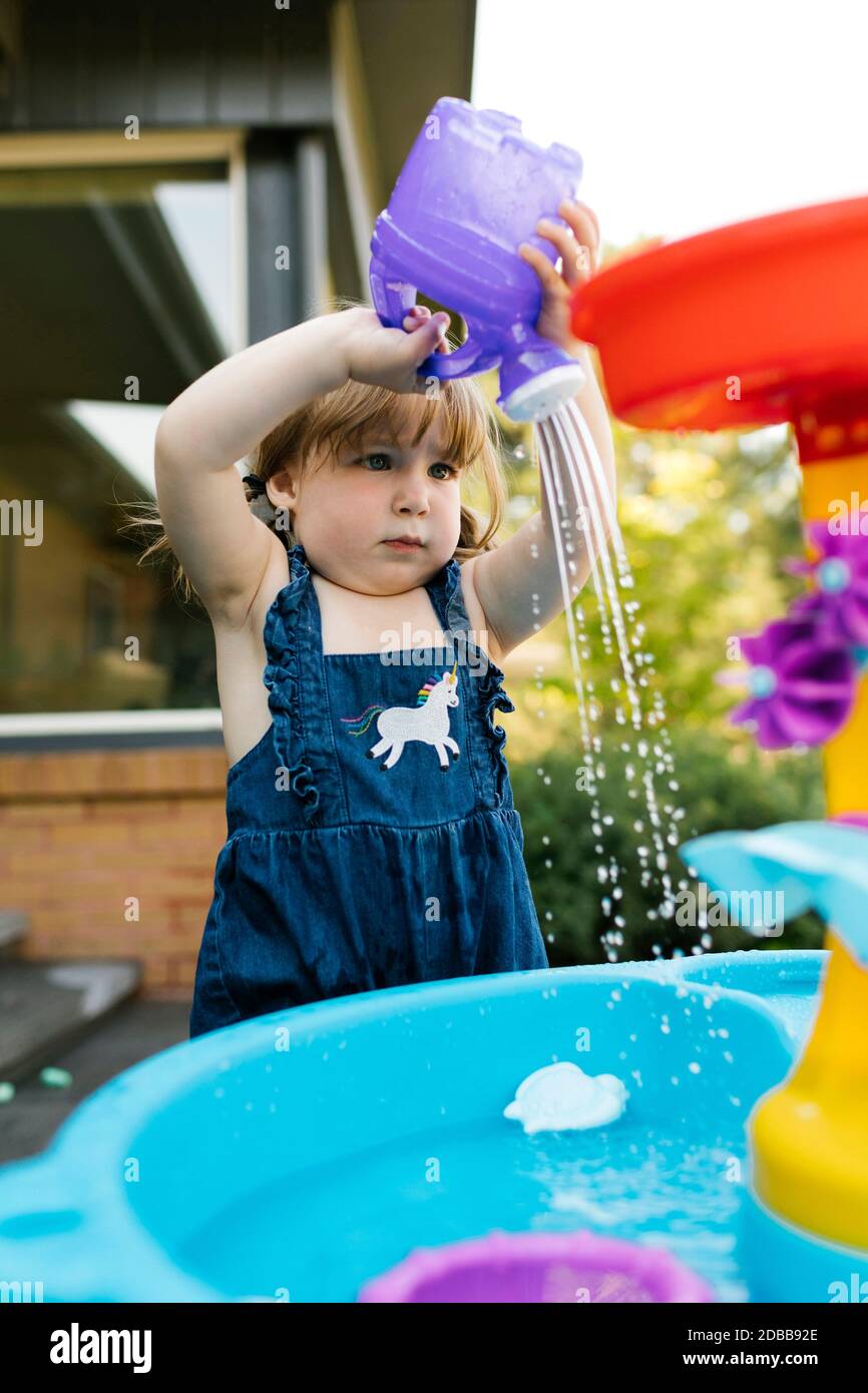 Petite fille (2-3) jouant avec de l'eau dans le jardin Banque D'Images