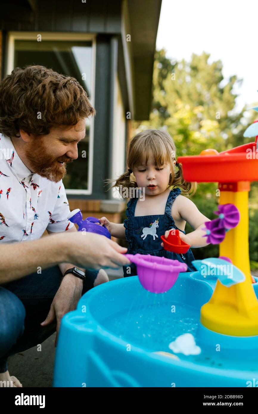 Père et petite fille (2-3) jouant avec l'eau dans le jardin Banque D'Images
