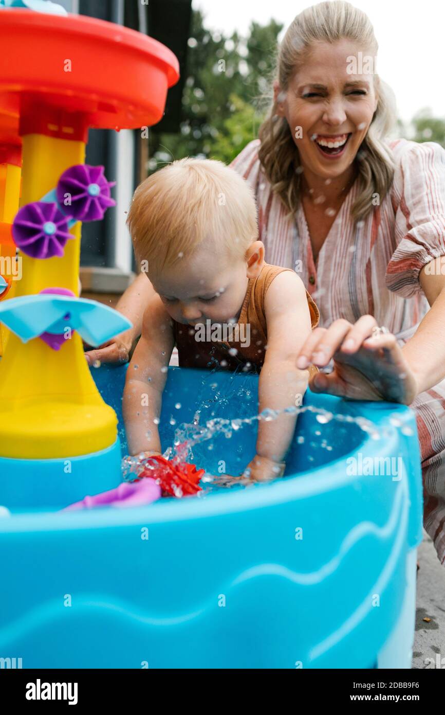 Mère avec bébé (18-23 mois) jouer avec l'eau dans le jardin Banque D'Images