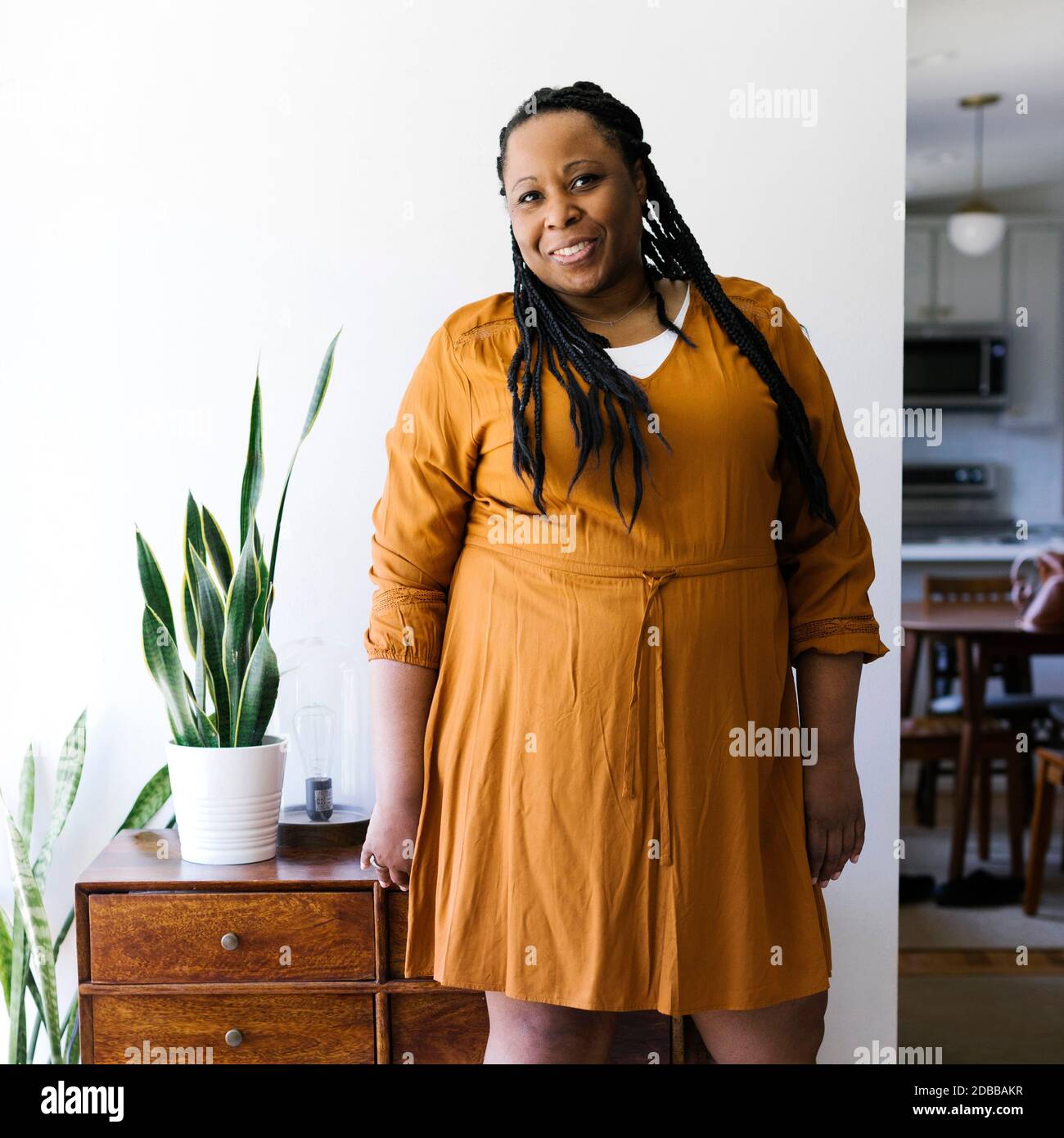 Portrait d'une femme souriante vêtue d'une robe orange à la maison Banque D'Images