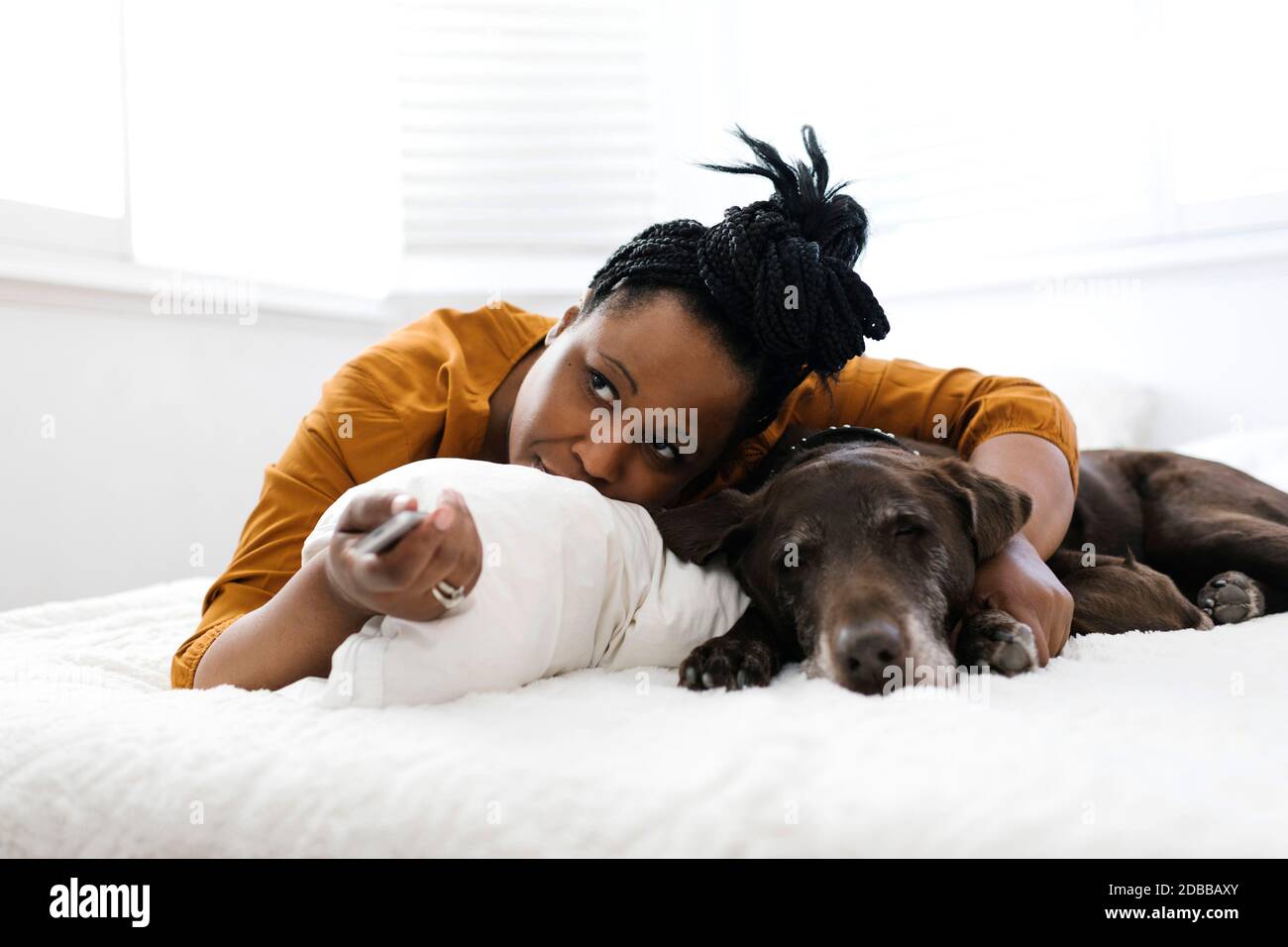Femme couché sur le lit avec un chien et regardant la télévision Banque D'Images