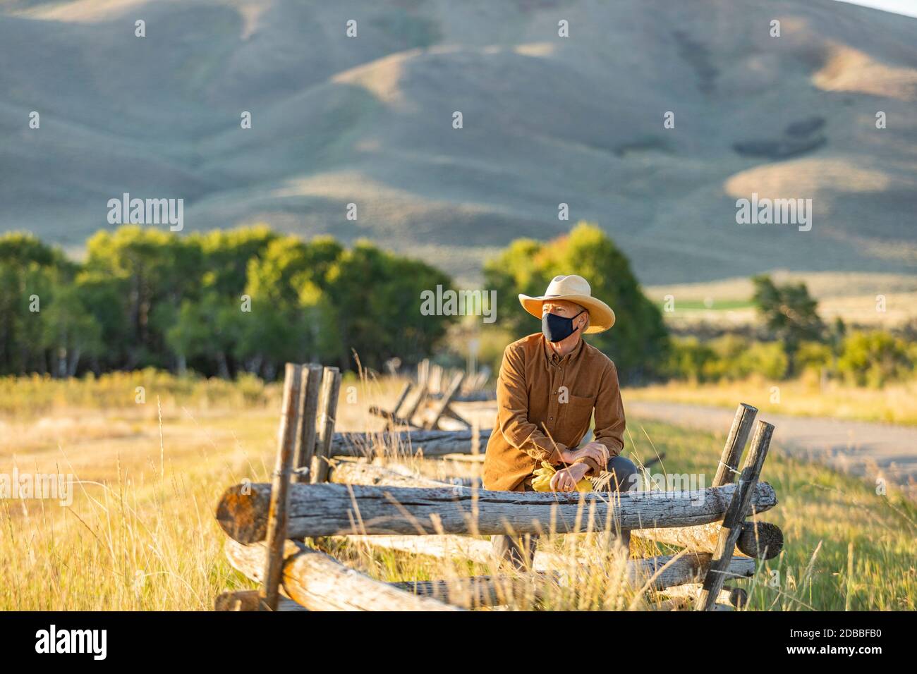 États-Unis, Idaho, Bellevue, Rancher dans le masque de visage appuyé contre la clôture sur le terrain Banque D'Images