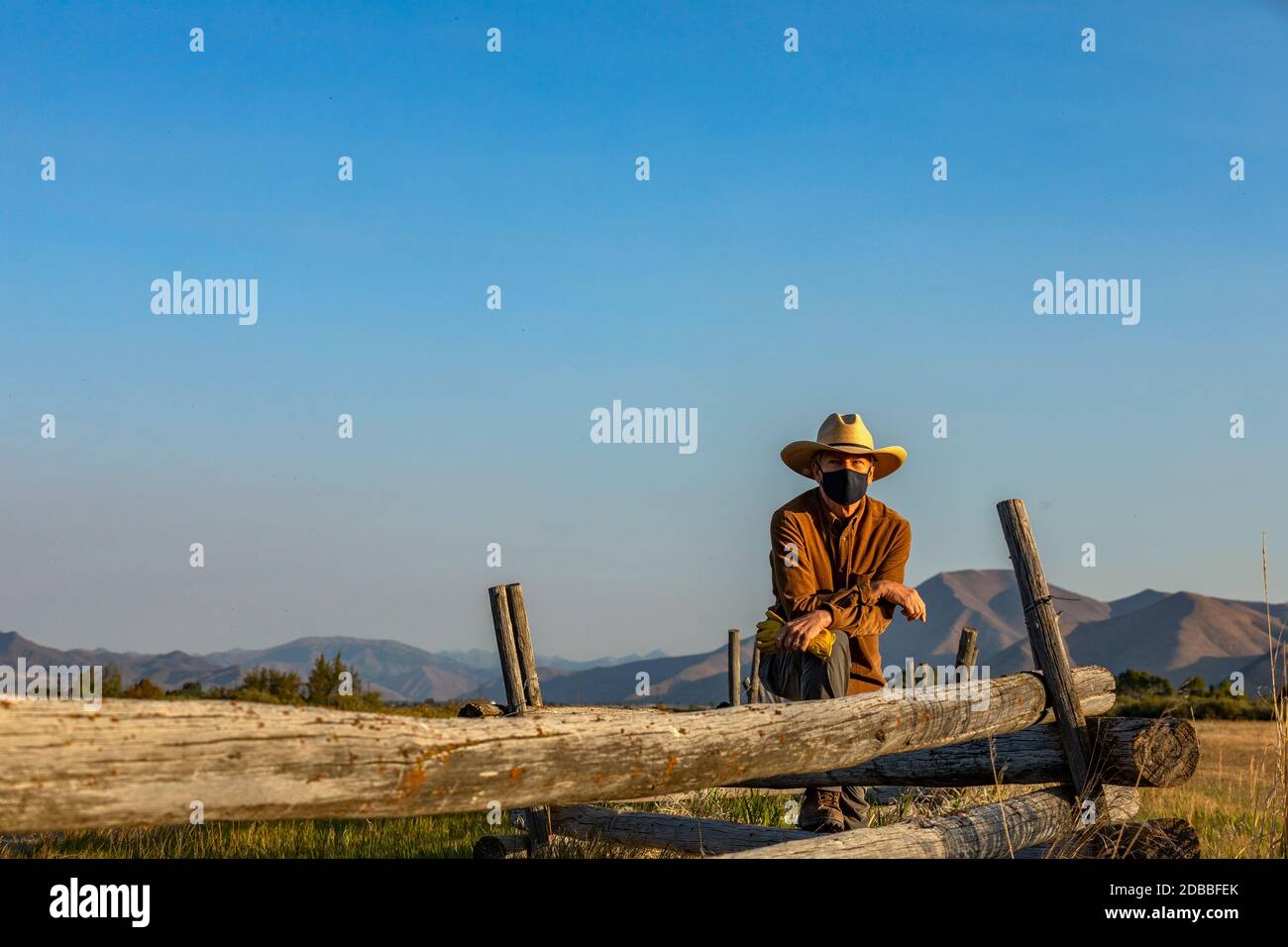 États-Unis, Idaho, Bellevue, Rancher dans le masque de visage appuyé contre la clôture sur le terrain Banque D'Images