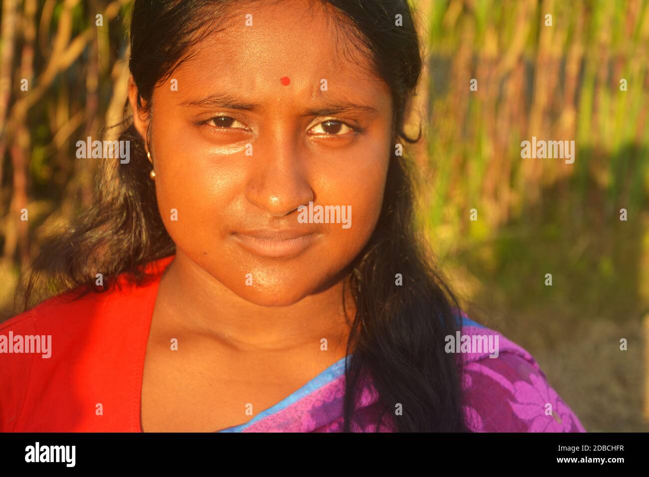 Gros plan d'une adolescente bengali indienne avec des cheveux longs et un bindi rouge sur son front et un sourire sur son visage, en se concentrant de manière sélective Banque D'Images