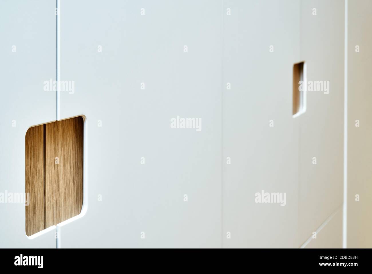 Détail de la garde-robe en gros plan. armoire moderne en bois avec portes-penderie plates à tirer sur les doigts. Armoires en contreplaqué plaqué chêne avec peinture gris clair ca Banque D'Images