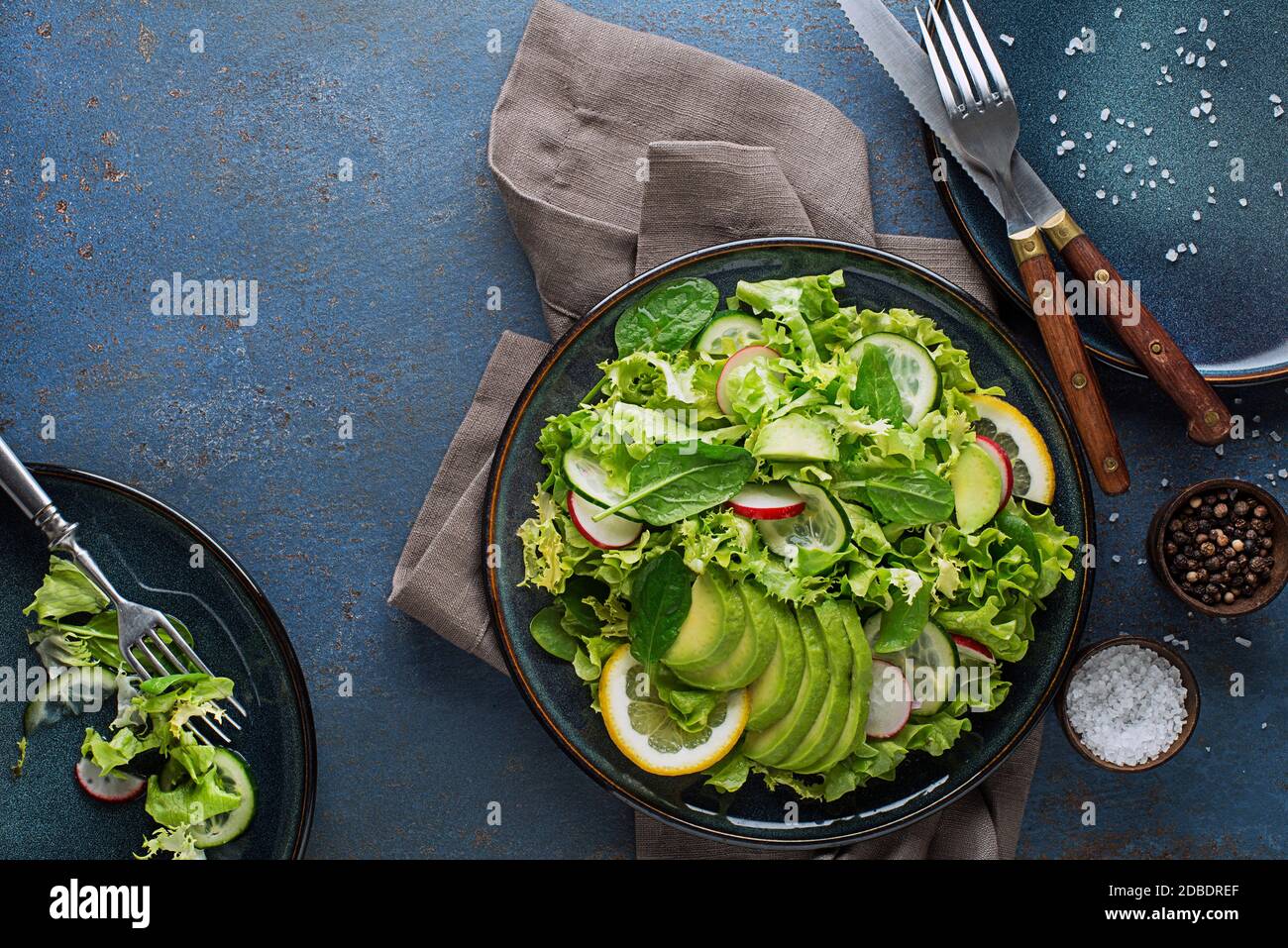 Salade verte avec avocat et légumes frais sur un bleu arrière-plan Banque D'Images