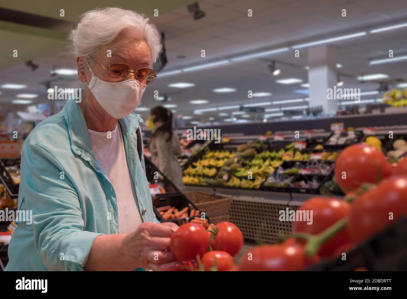 Femme âgée avec masque facial au supermarché Banque D'Images