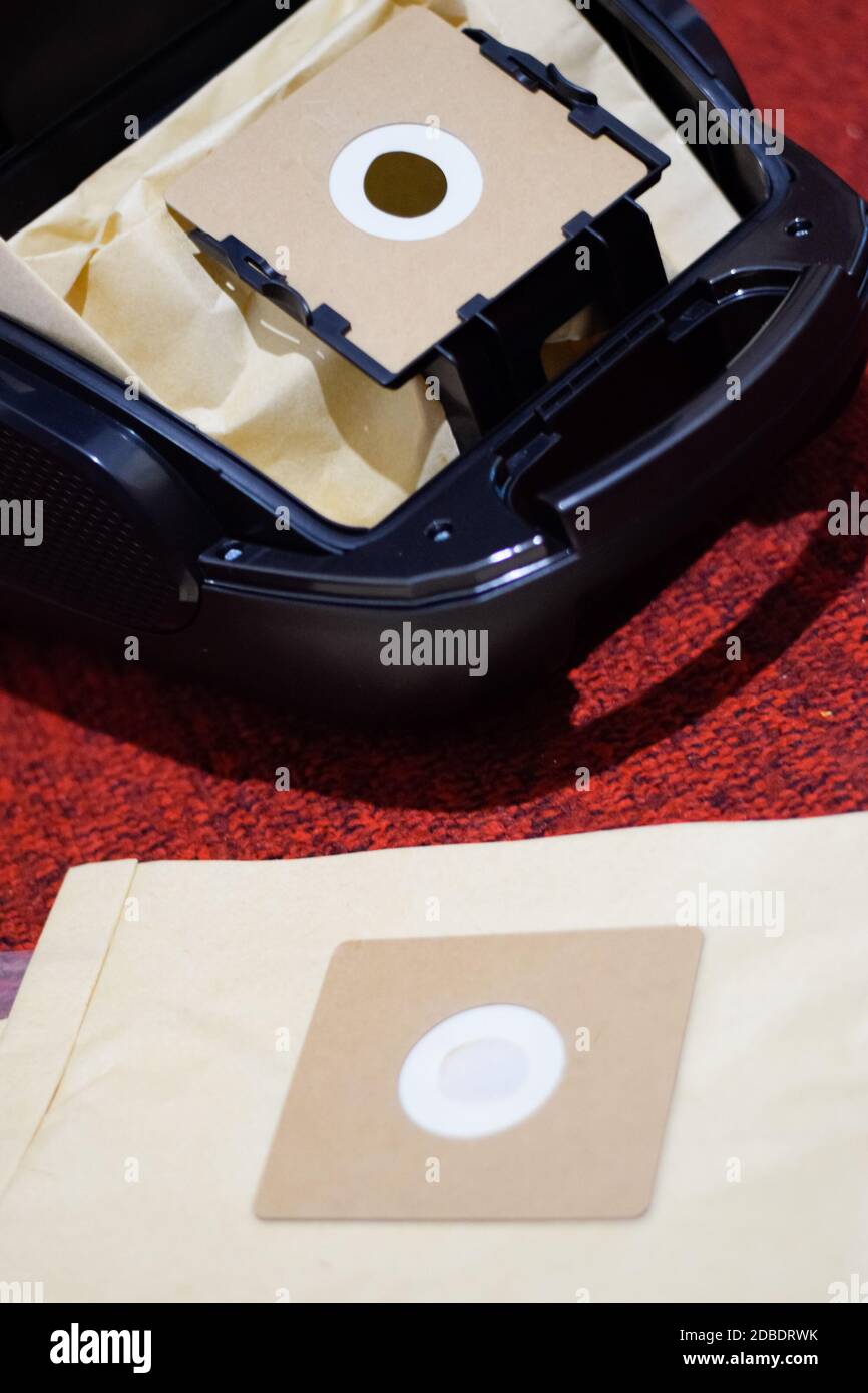 Un aspirateur avec un jeu de brosses et de sacs. Un aspirateur sur le tapis rouge. Banque D'Images