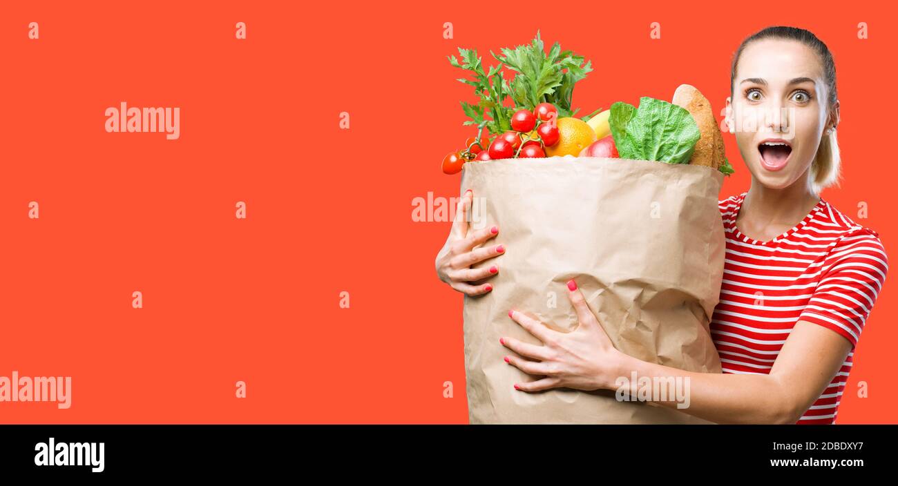 Joyeuse jeune femme heureuse tenant un énorme sac d'épicerie rempli de légumes frais délicieux, de nourriture et de saine alimentation concept Banque D'Images