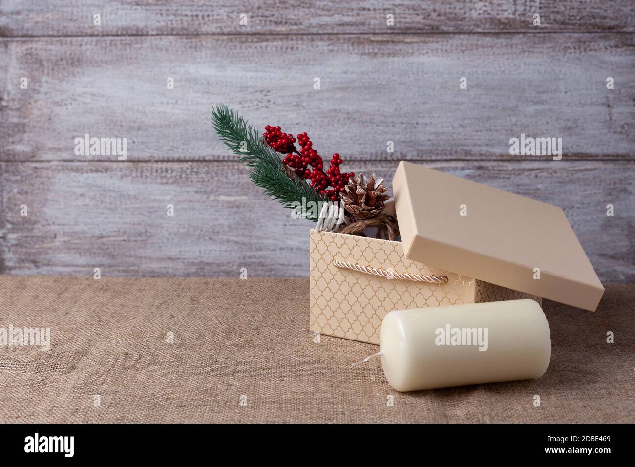 Maquette de boîte cadeau beige, branche arbre de Noël avec décorations, bougie vanille sur fond de bois Banque D'Images