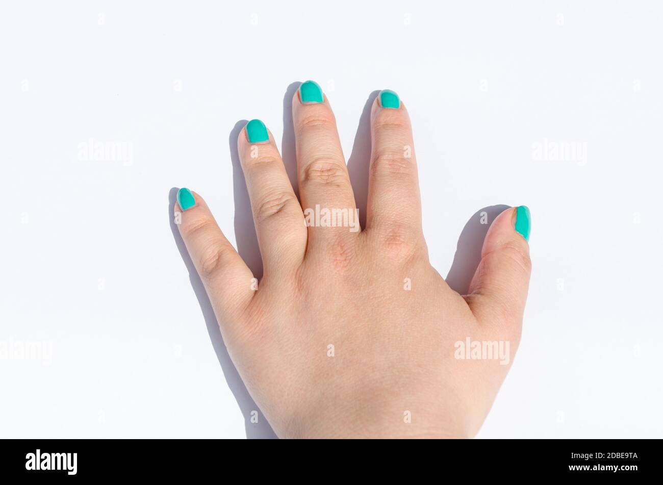 La main féminine avec nail design vert sur fond blanc. Banque D'Images