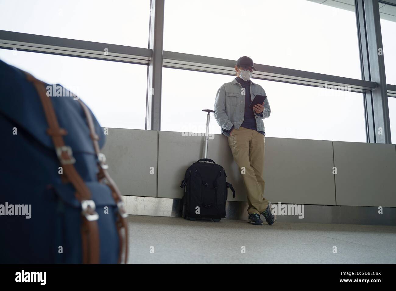 jeune homme asiatique homme voyageur de l'air lisant e-livre en utilisant un lecteur électronique en attente d'embarquement dans le terminal de l'aéroport Banque D'Images