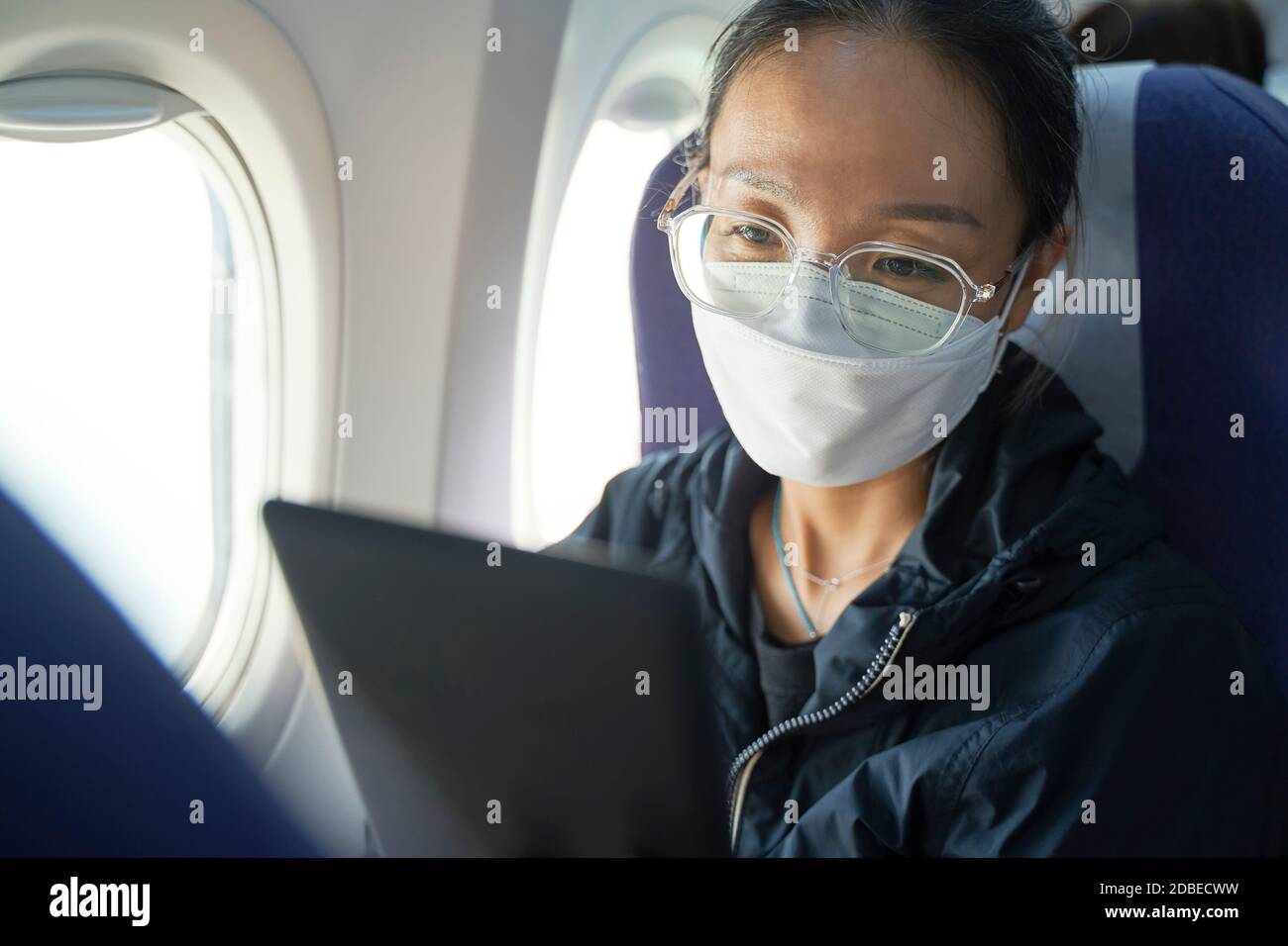 femme asiatique passager assis en cabine de lecture d'avion ebook à l'aide d'un appareil électronique Banque D'Images femme asiatique passager assis en cabine de lecture d'avion ebook à l'aide d'un appareil électronique Banque D'Images