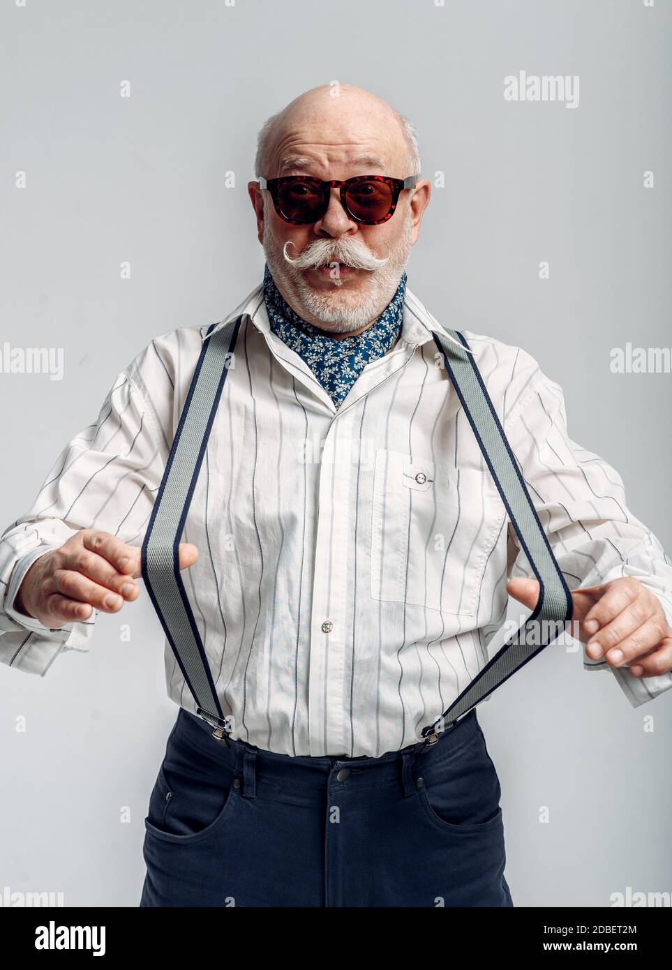 Homme âgé tendance en pantalon avec bretelles et lunettes de soleil, fond  gris. Senior mature regardant la caméra en studio, dude Photo Stock - Alamy