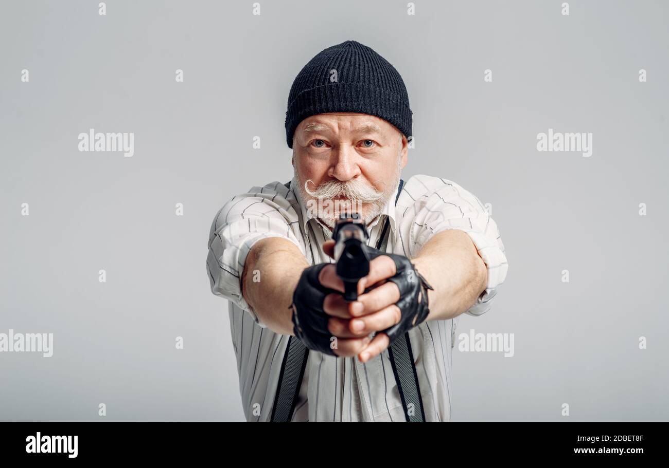 Homme âgé pose avec un fusil sur fond gris, gangster. Mature senior dans le  chapeau tient larme, voleur dans le vieux âge Photo Stock - Alamy