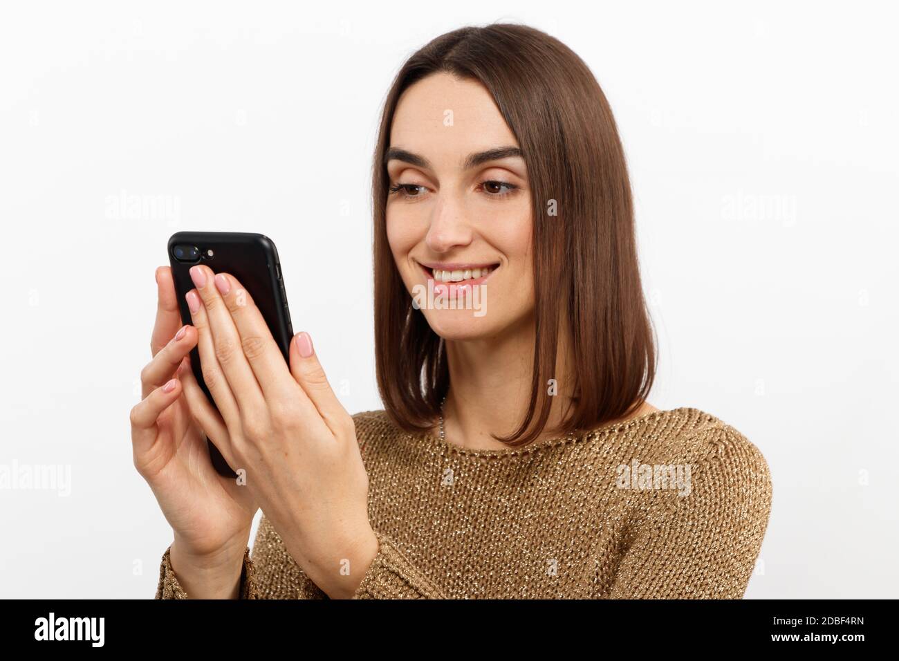 Portrait avant d'une jeune femme souriante utilisant un téléphone portable contre arrière-plan blanc Banque D'Images