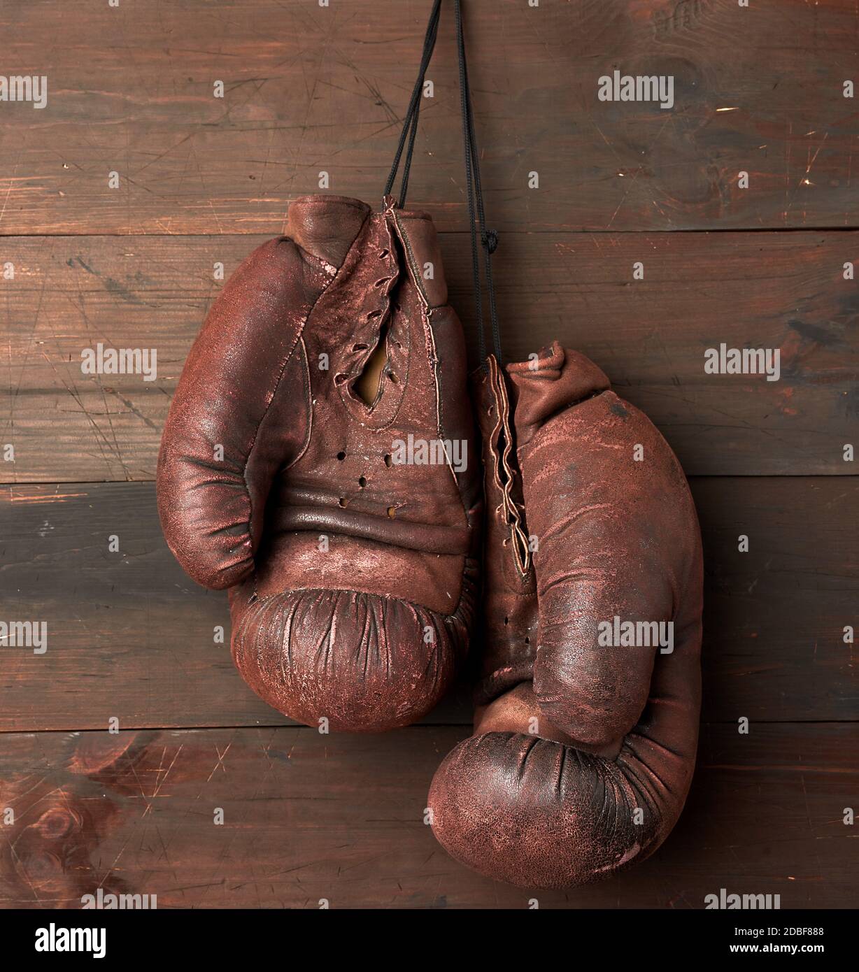 paire de gants de boxe en cuir marron accrochés à un mur en bois, équipement de sport Banque D'Images