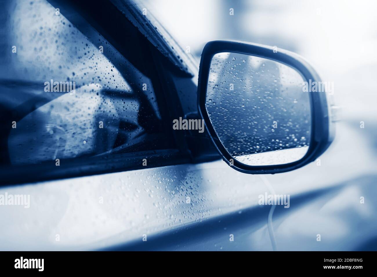 La voiture argentée légère roule rapidement par mauvais temps et il y a des gouttes de pluie claires sur les glaces et sur le rétroviseur. Mélancolie. Banque D'Images