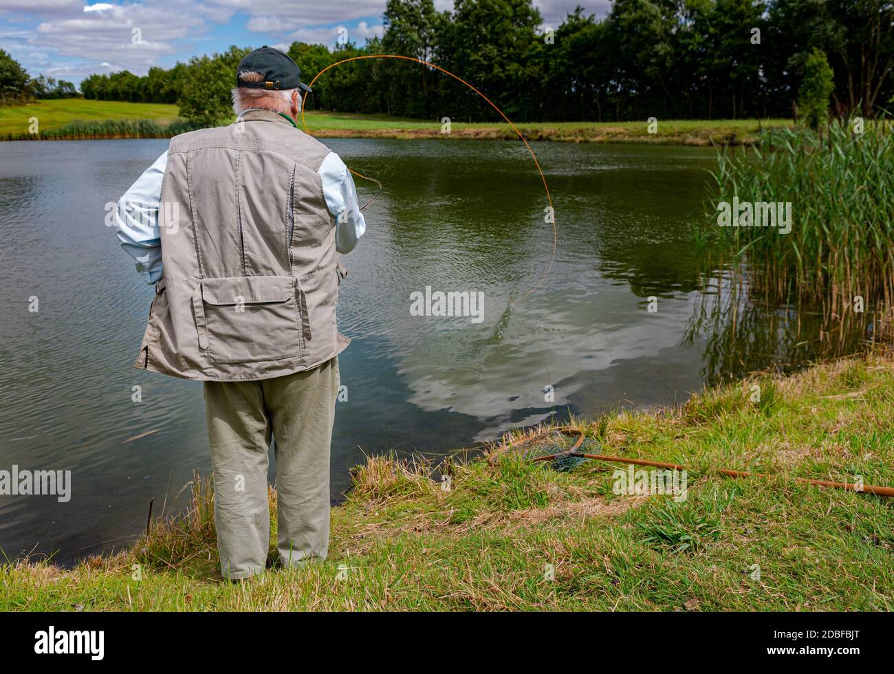 Lincolnshire, Royaume-Uni - M. Barry Grantham, un instructeur de pêche à la mouche, jetant une ligne de mouche à travers un lac de truite pour la truite arc-en-ciel Banque D'Images Lincolnshire, Royaume-Uni - M. Barry Grantham, un instructeur de pêche à la mouche, jetant une ligne de mouche à travers un lac de truite pour la truite arc-en-ciel Banque D'Images