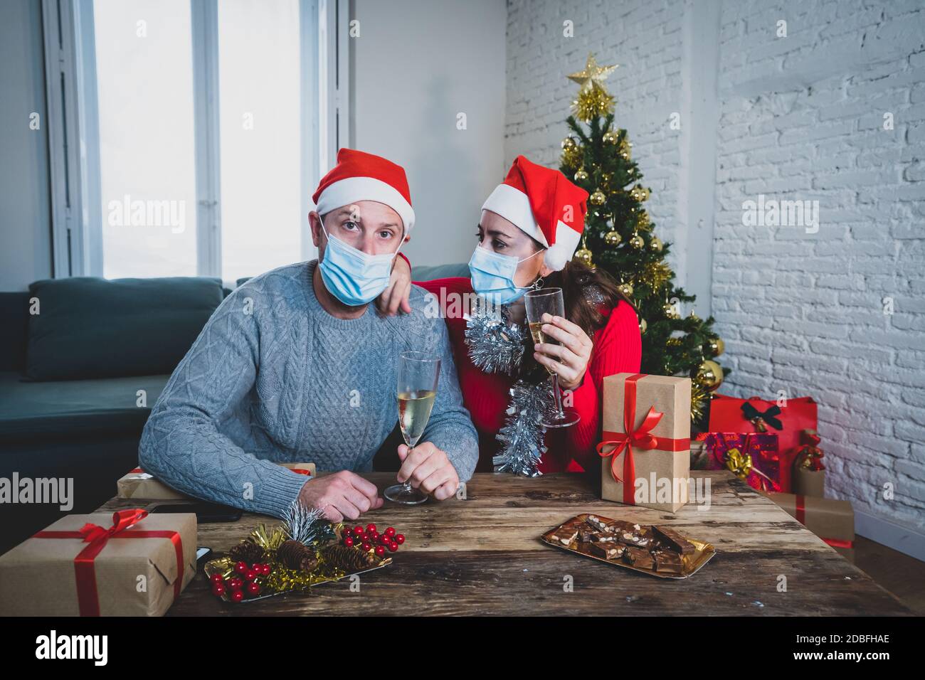 Triste couple avec masque en auto-isolation lors d'un appel vidéo avec une famille manquante célébrant noël et le nouvel an face à face. Célébrations virtuelles et COV Banque D'Images