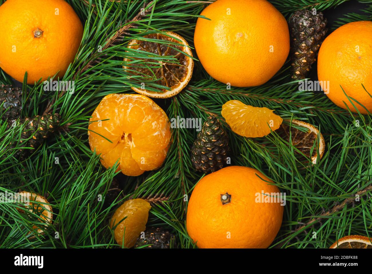 Des tangerines pelées avec des branches et des cônes en gros plan. Carte postale pour Noël et le nouvel an. Vue de dessus. Banque D'Images