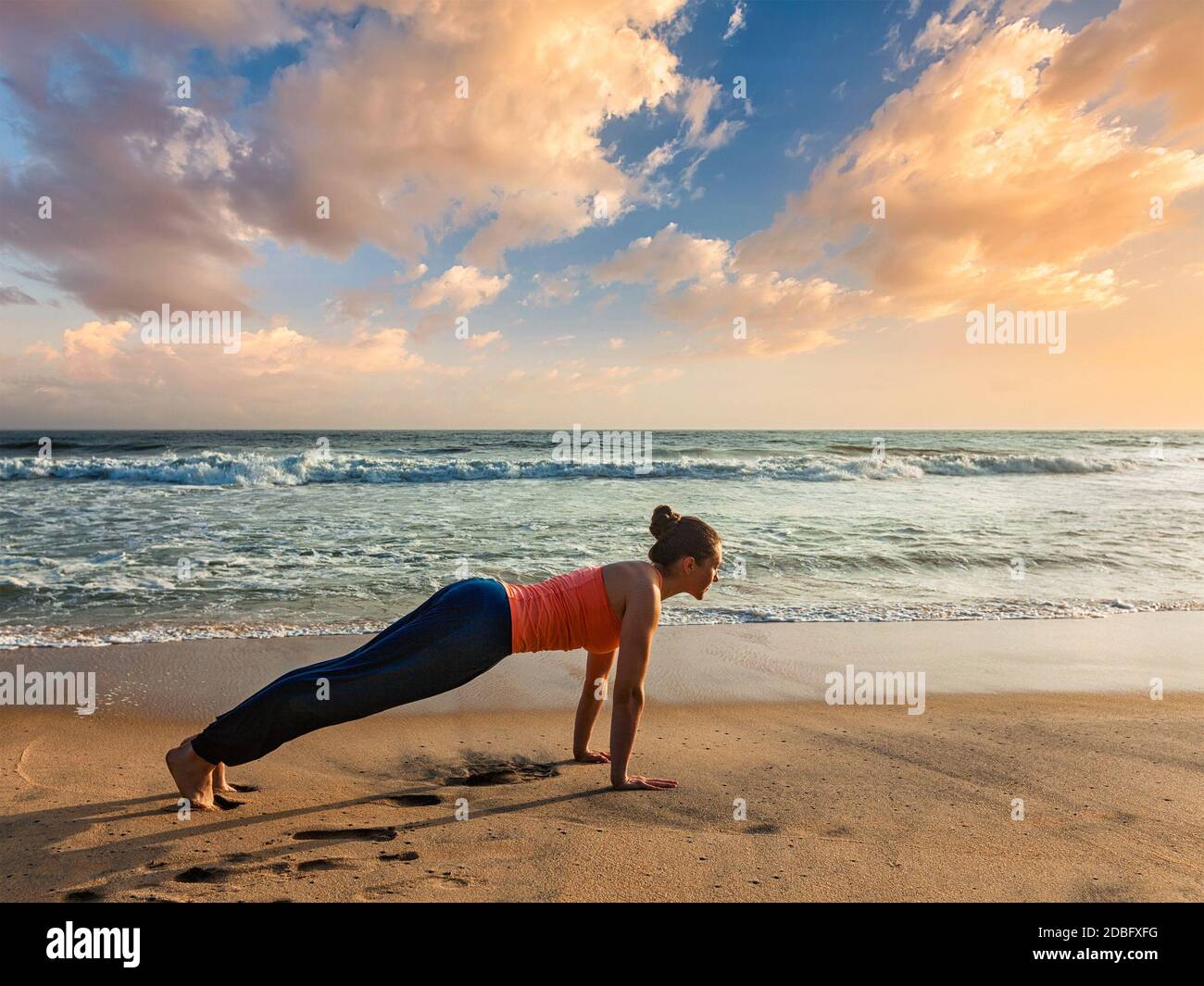 Belle femme sportive pratique Ashtanga Vinyasa yoga Surya Namaskar Sun Salutation asana Kumbhakasana plank poser à l'extérieur à la plage au coucher du soleil. Va Banque D'Images