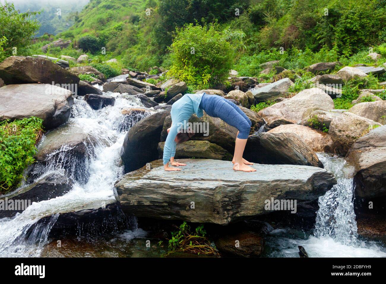 Yoga à l'extérieur - jeune femme sportive faisant Ashtanga Vinyasa Yoga asana Urdhva Dhanurasana - posture de l'arc vers le haut au tropical cascade Banque D'Images