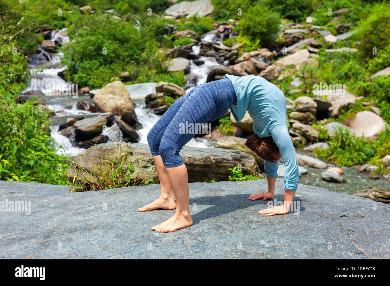 Yoga à l'extérieur - jeune femme sportive faisant Ashtanga Vinyasa Yoga asana Urdhva Dhanurasana - posture de l'arc vers le haut au tropical cascade Banque D'Images
