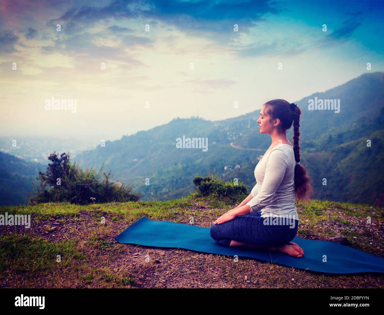 Exercice de yoga en plein air - femme faisant Yoga asana Virasana Hero pose dans l'Himalaya en Inde au coucher du soleil. Image style boxer style rétro avec filtre Banque D'Images