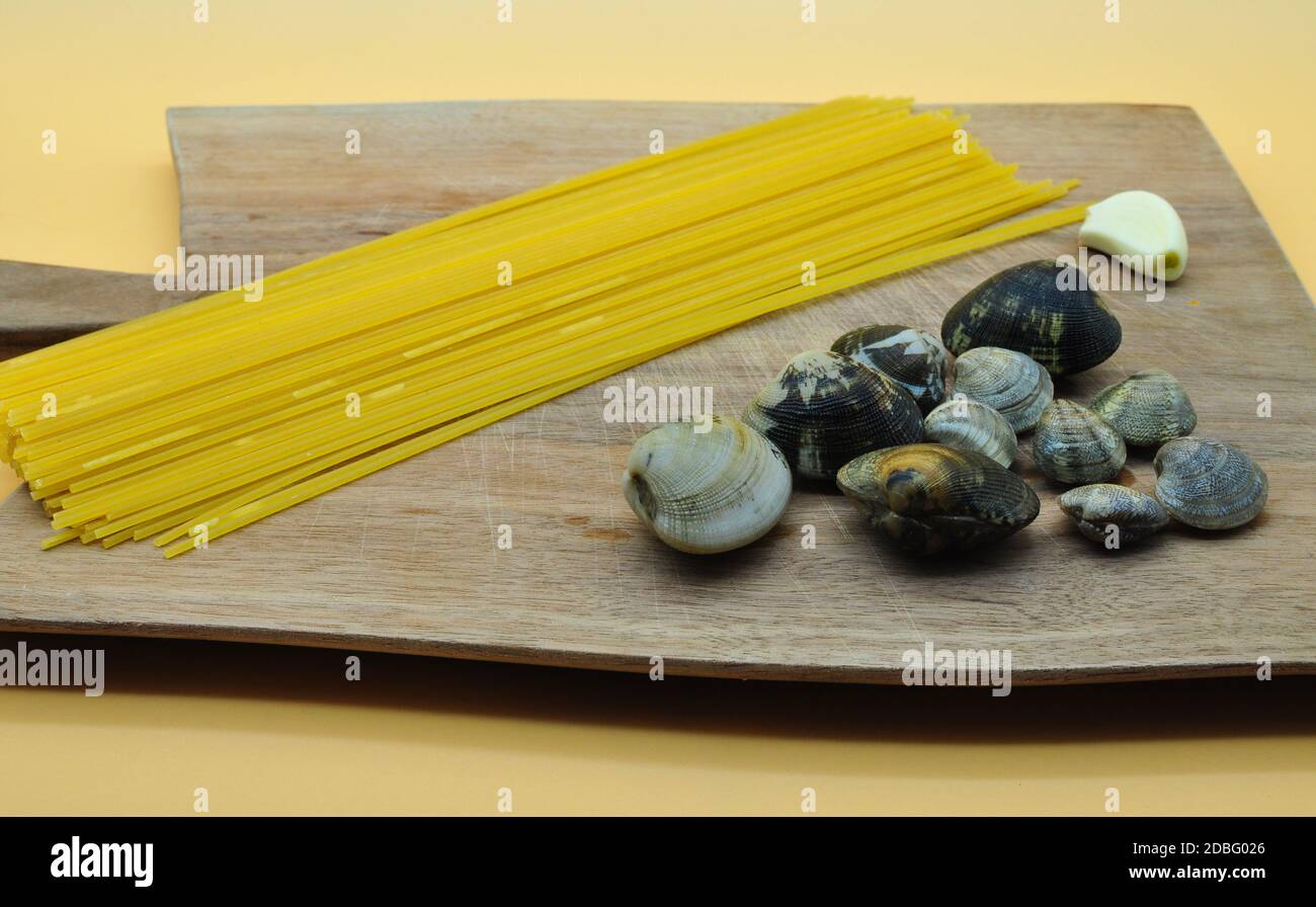 Tout ce dont vous avez besoin pour cuisiner des spaghettis appétissants avec des palourdes avec la recette italienne parfaite, tous placés sur un tableau de découpe élégant de woo noble Banque D'Images