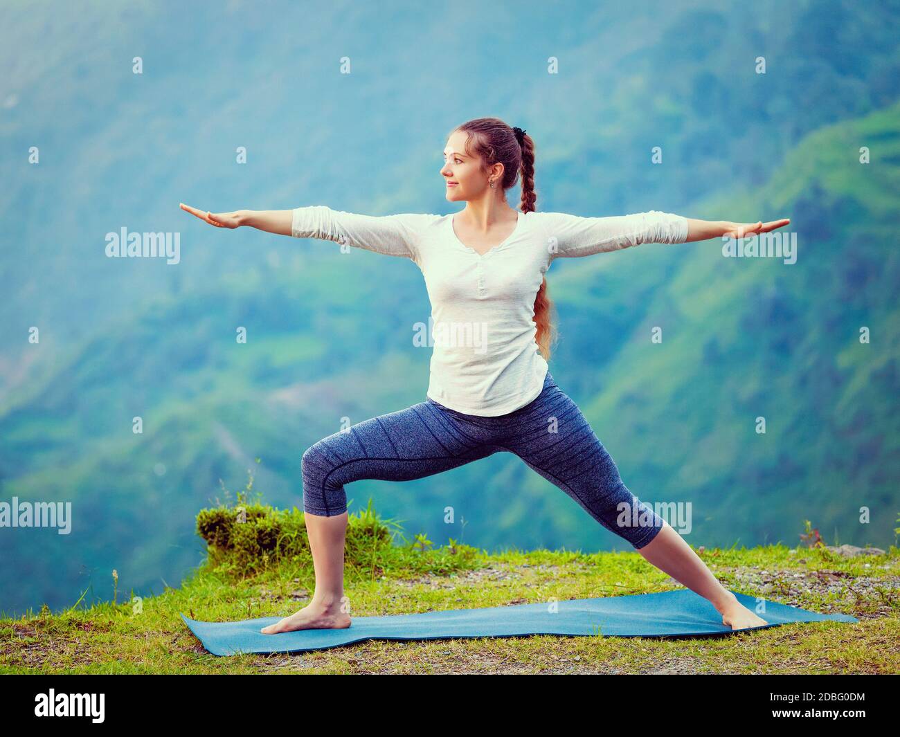 Yoga à l'extérieur - femme sportive faisant Ashtanga Vinyasa Yoga asana Virabhadrasana 2 posture du guerrier en montagne. Effet rétro vintage filtré h Banque D'Images