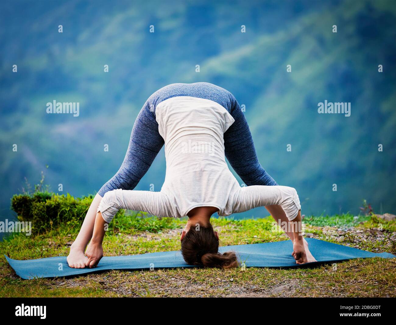Exercice de yoga à l'extérieur - femme faisant Ashtanga Vinyasa Yoga asana Prasarita padottanasana D - large legged avant de se pencher posent à l'extérieur. Rétro rétro e Banque D'Images