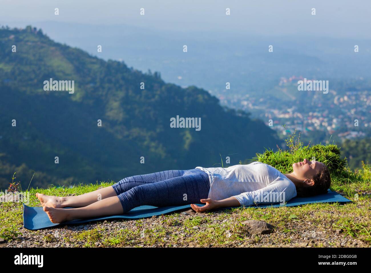 Femme se détend dans le yoga asana Savasana - cadavre pose à l'extérieur dans l'Himalaya. Himachal Pradesh, Inde Banque D'Images