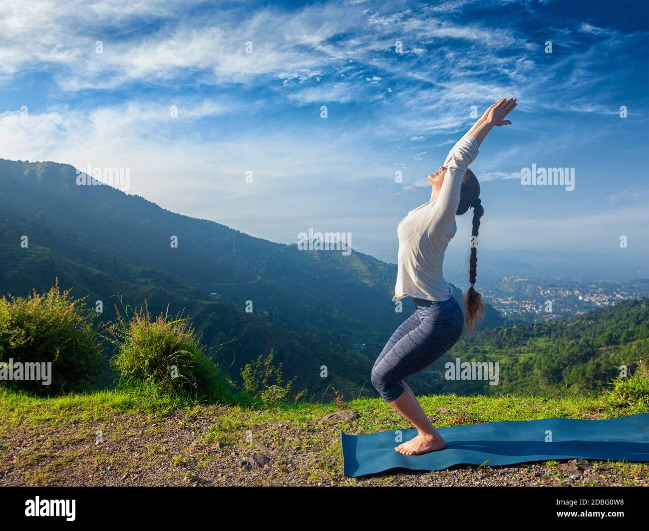 Jeune femme sportive faisant du yoga asana Utkatasana (pose de chaise) en plein air dans les montagnes Himalaya le matin. Himachal Pradesh, Inde Banque D'Images