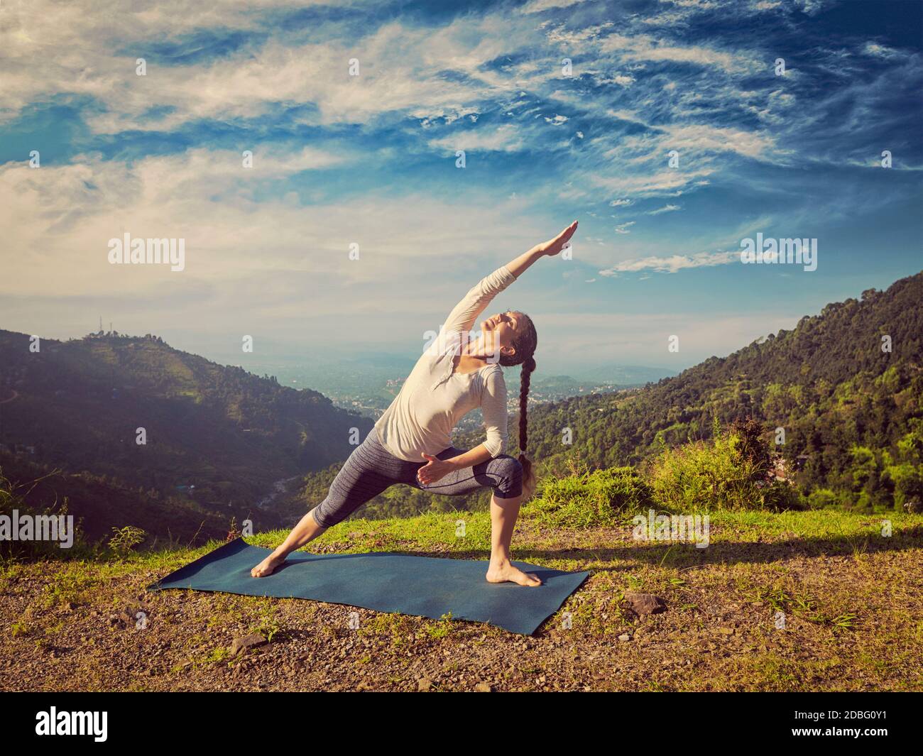 Vintage rétro effet hipster image de style sportif femme Pratiques yoga asana Utthita Parsvakonasana - posture latérale prolongée extérieur dans le support Banque D'Images