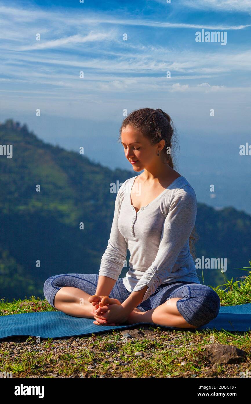 Femme sportive pratique le yoga asana Baddha Konasana - angle relié pose à l'extérieur dans les montagnes de l'Himalaya dans le matin avec le ciel. Himachal Pradesh, in Banque D'Images