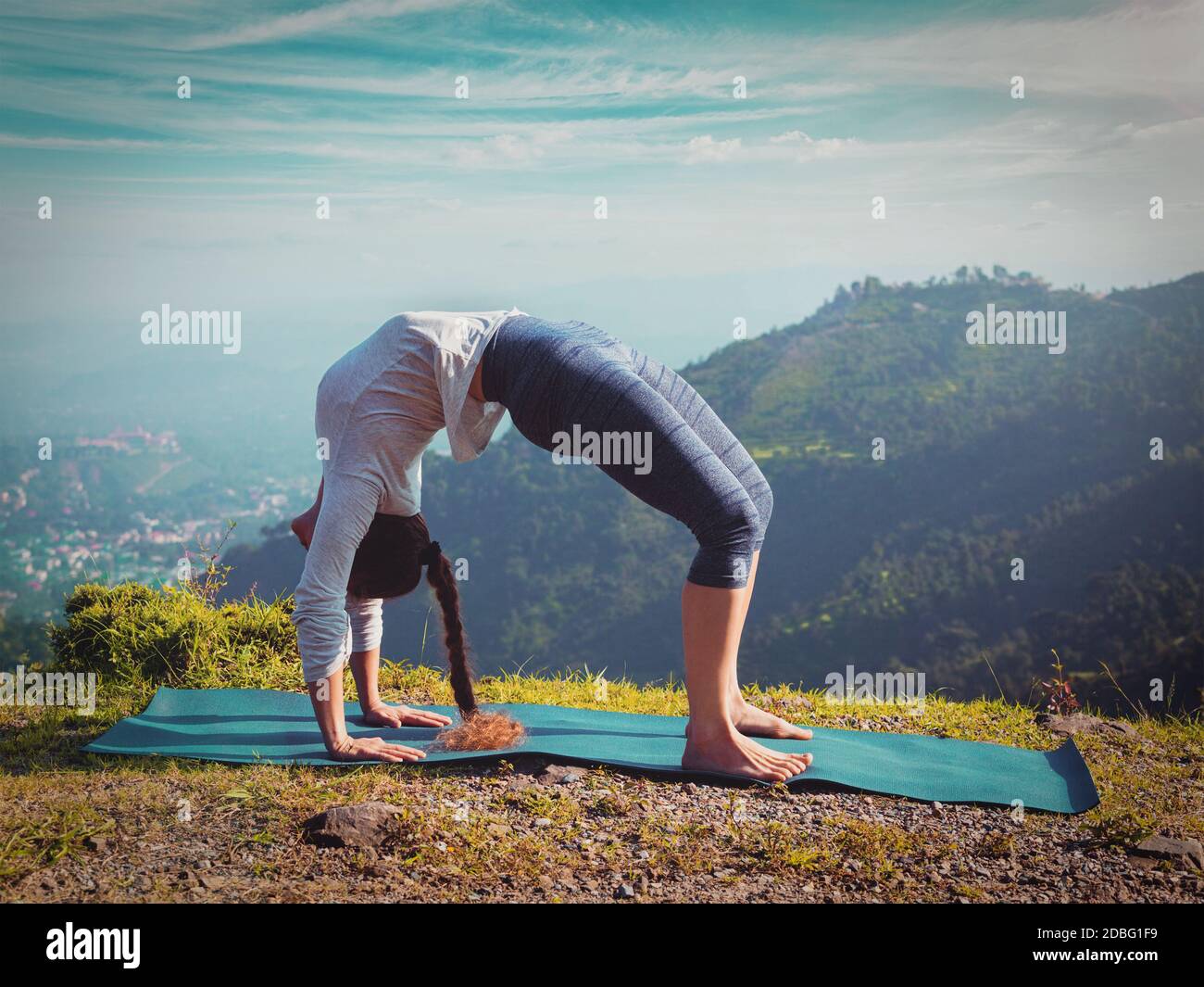 Yoga à l'extérieur - jeune femme sportive faisant Ashtanga Vinyasa Yoga asana Urdhva Dhanurasana - posture de l'arc vers le haut - po Montagnes de l'Himalaya dans la matinée Banque D'Images