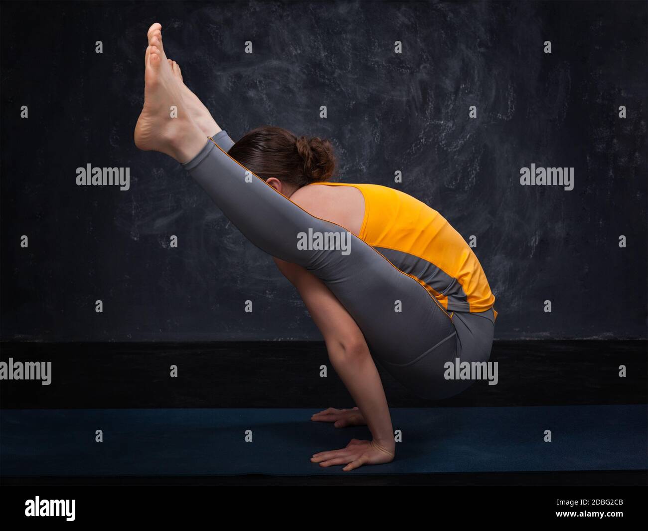 Belle tenue sportive yogini femme pratique yoga asana titibhasana - pose firefly sur fond sombre Banque D'Images