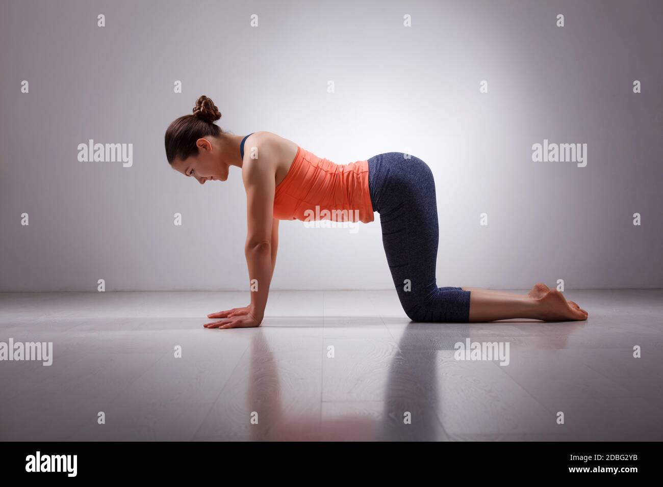 Belle tenue sportive yogini femme pratique yoga asana bitilasana - la vache pose un léger échauffement pour la colonne vertébrale (également appelé posture chat-vache) en studio Banque D'Images
