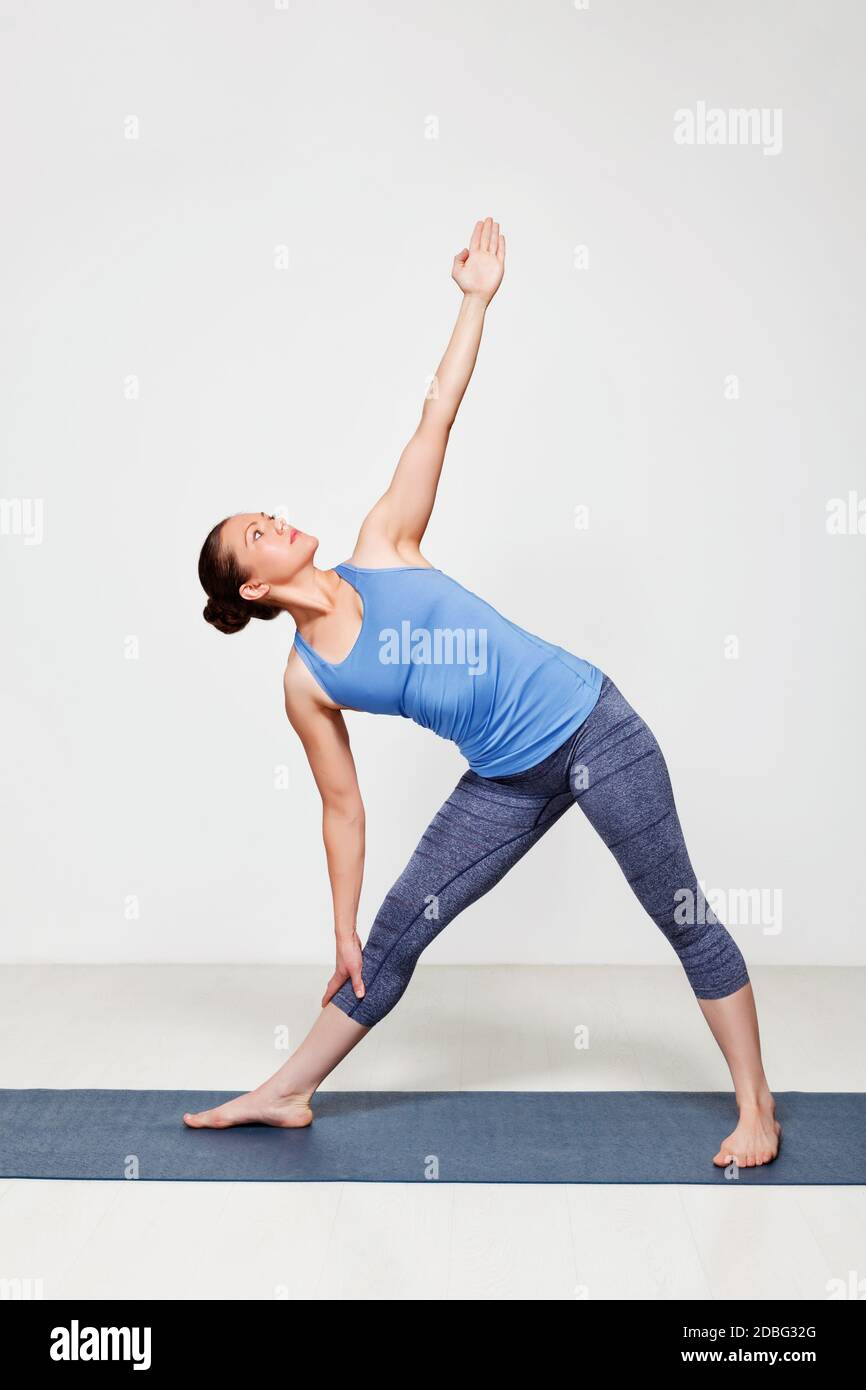 Belle femme sportive pratique yoga asana utthita trikonasana - triangle étendu pose débutant variation Banque D'Images