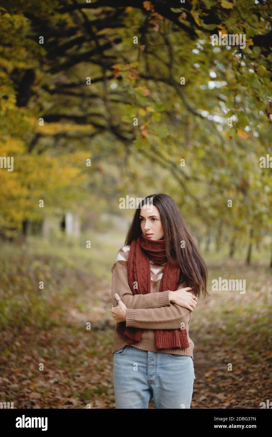 Belle femme aux cheveux longs dans un foulard chaud dans le parc d'automne. Banque D'Images