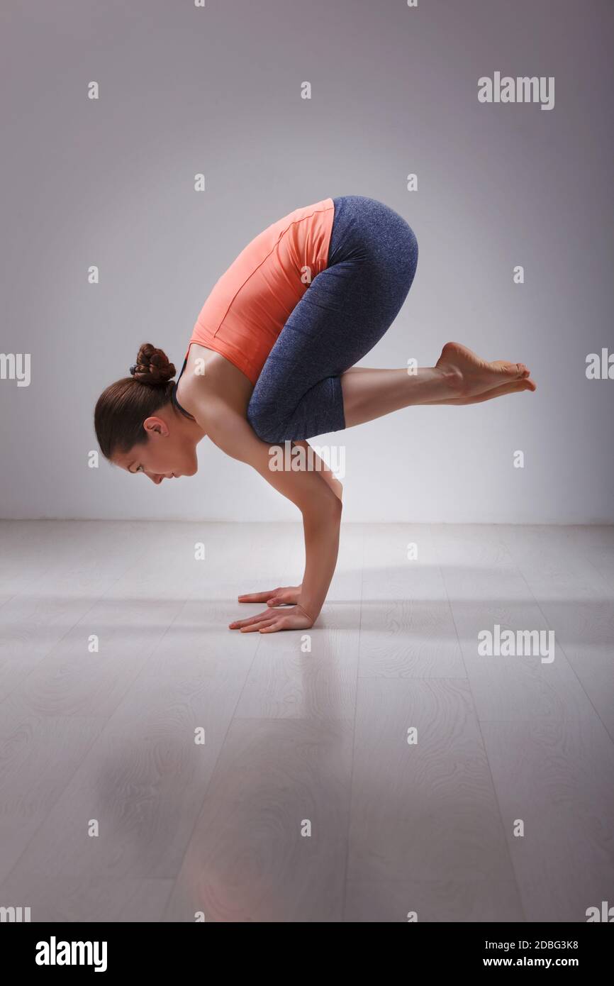 Belle tenue sportive yogini femme pratique yoga asana Bakasana - la grue pose l'équilibre du bras en studio Banque D'Images