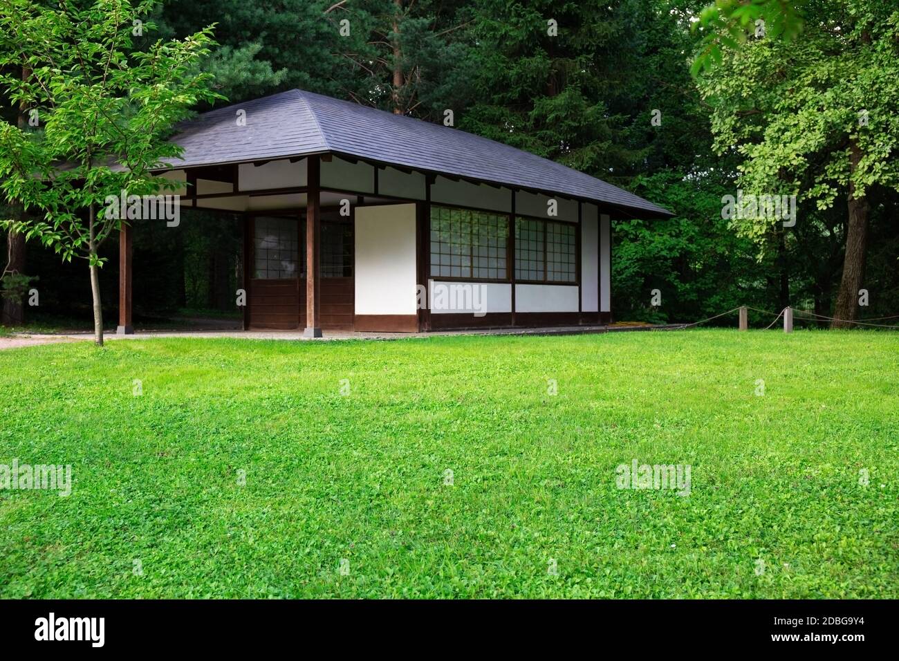 Architecture japonaise traditionnelle.la façade d'une petite maison japonaise traditionnelle parmi les arbres, un jardin et une pelouse verte. Maison japonaise en bois Banque D'Images