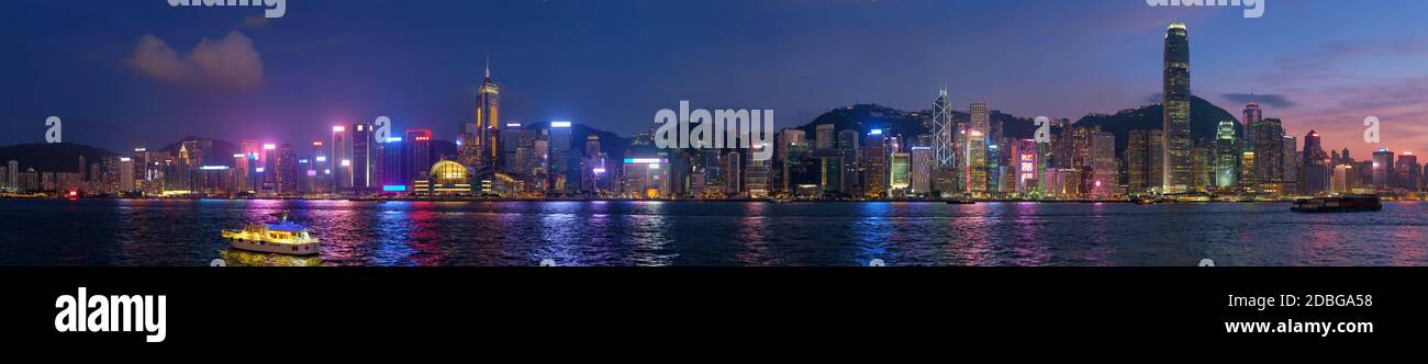 Panorama de la ville de Hong Kong gratte-ciel du centre-ville au-dessus du port de Victoria dans la soirée illuminés bateaux et ferries touristiques. Hong Kong, C. Banque D'Images