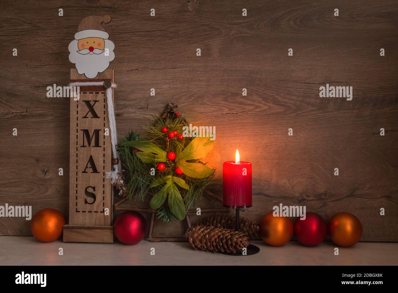Décoration de Noël avec bougie rouge brûlante, Père Noël en bois, sapin de Noël, boules sur table, arrière-plan en bois pour le texte Banque D'Images