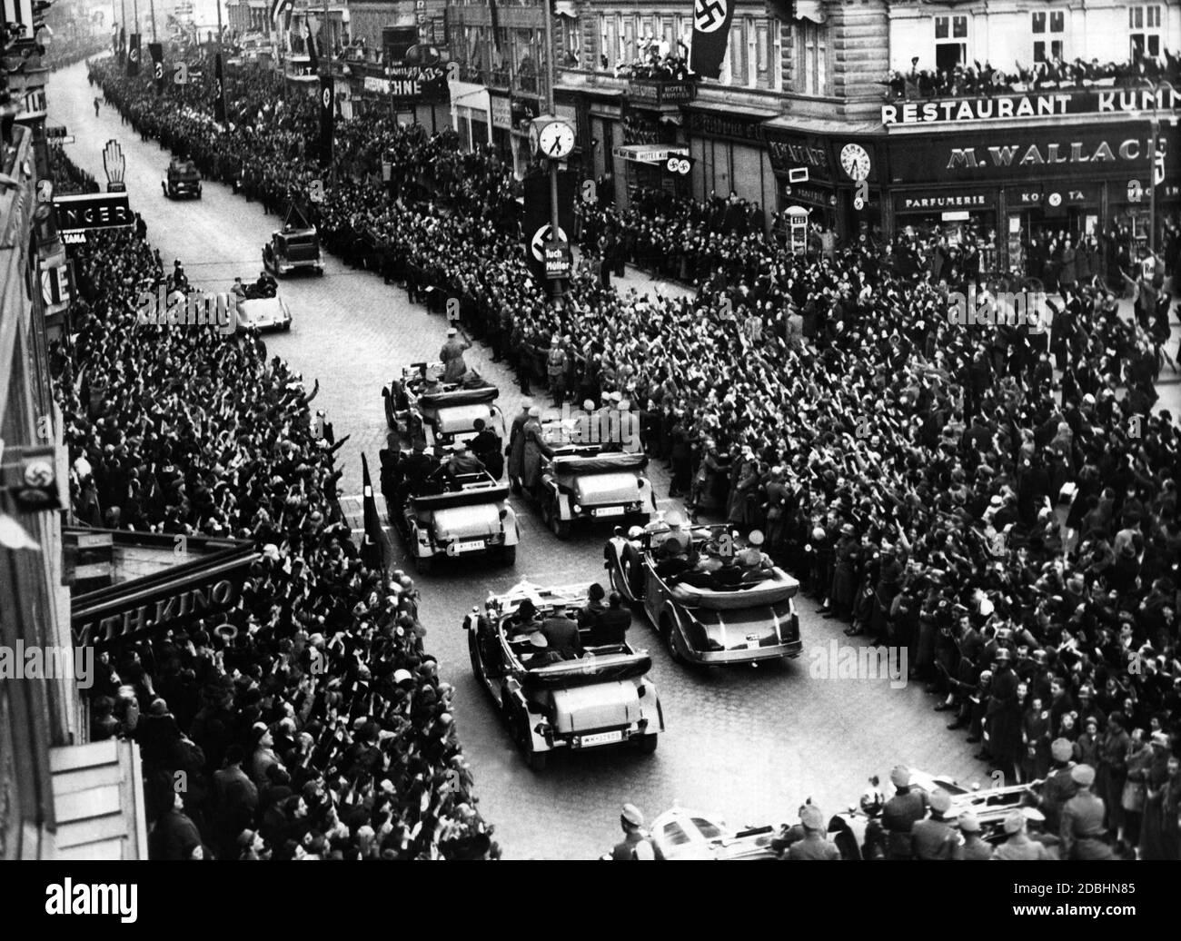 Hitler au milieu de la population viennoise qui applaudit à son entrée à Vienne après l'Anschluss d'Autriche en 1938, suivi d'une escorte avec le personnel de sécurité qui a sauté des voitures à chaque arrêt, le soi-disant Fuehrerbegleitkommando (Fuehrer Escort Command). Banque D'Images