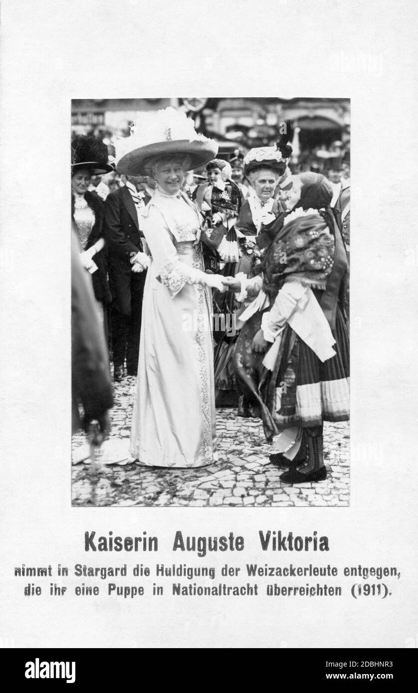 L'impératrice Auguste Viktoria est accueillie par les Weizacker en 1911 à Stargard, en Pomerania (aujourd'hui Szczecinski, en Pologne). Ils lui ont présenté une poupée dans leur costume national, que l'impératrice tient dans sa main. Banque D'Images