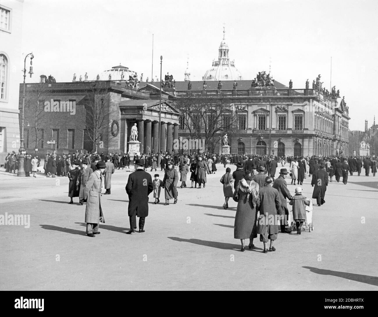 Passants la rue Unter den Linden à Berlin en face de la Neue Wache (au centre de la photo) et du Zeughaus (juste derrière) en 1940. En arrière-plan, le sommet de la cathédrale de Berlin. Banque D'Images